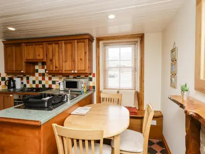 a kitchen with a wooden table and a dining room at 2 Burnside Place in Kirkcudbright