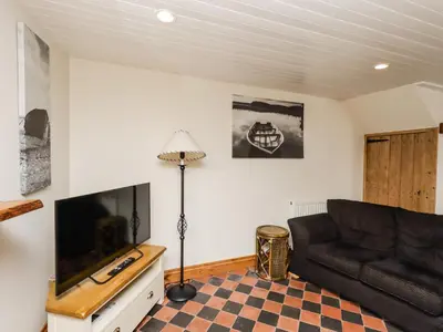 a living room with a couch and a flat screen tv at 2 Burnside Place in Kirkcudbright