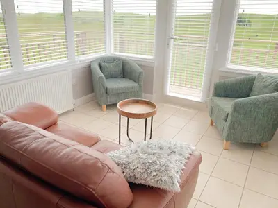 a living room with a leather couch and two chairs at Float bay view in Stranraer