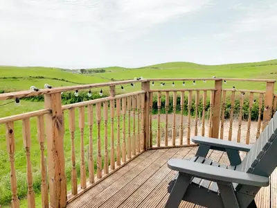 a wooden deck with a bench and a fence at Float bay view in Stranraer