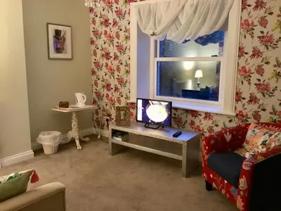 a living room with a tv on a table and a window at The Glen Mona Hotel in Maughold