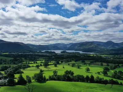 a view of a green field with a lake and mountains at Norton in Keswick