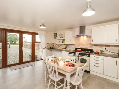 a kitchen with a table and chairs in a kitchen at Bramblewood Cottage in Crookdake