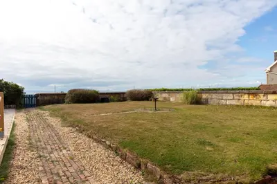 a garden with a stone wall and a brick road at Shore View - Donnini Apartments in Prestwick