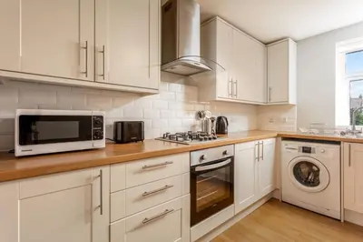 a kitchen with white cabinets and a microwave at Shore View - Donnini Apartments in Prestwick
