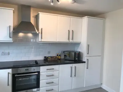 a kitchen with white cabinets and a stove top oven at Harbourside in Garlieston