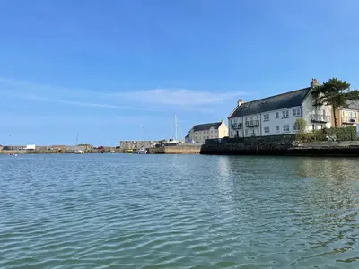 a large body of water with a building and houses at Harbourside in Garlieston