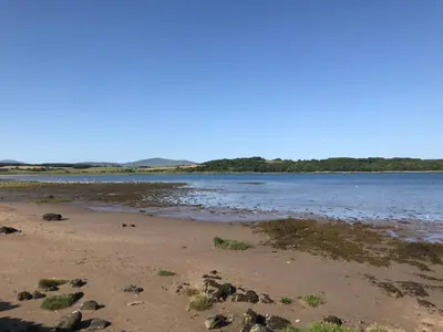 a body of water with rocks on the beach at Harbourside in Garlieston