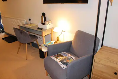 a living room with a chair and a desk with a computer at Woodlands Country House & Cottage in Ireby