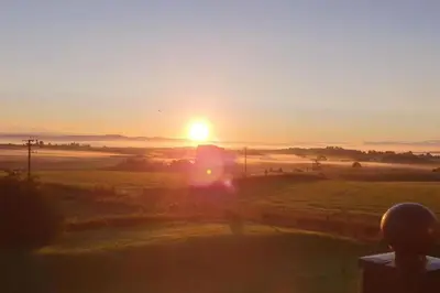 a sunset over a field with the sun in the sky at Ullswater Suite in Penrith