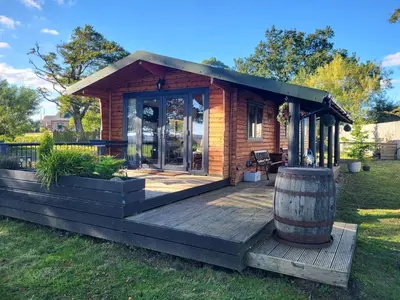 a tiny house with a barrel on a deck at Cosy wood cabin in rural area near national park in Cumnock