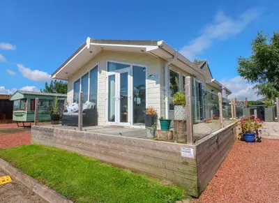 a small house with glass doors and a porch at A and C Lodge Plot 21 2 double bedrooms PLOT 21 With HOT TUB 1 pet only No Commercial Vans 4pm check in in High Hesket