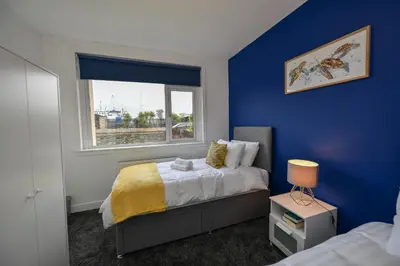 a blue bedroom with a bed and a window at Greensleeves Place in Troon