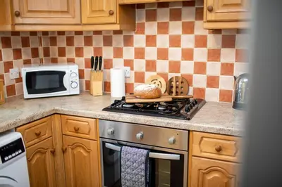 a kitchen with a stove and a microwave at Adrian House, near Hospital, easy parking + garden in Carlisle