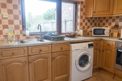 a kitchen with a sink and a washing machine at Adrian House, near Hospital, easy parking + garden in Carlisle