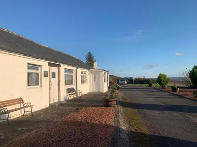 a building with a bench next to a street at Solway Firth View in Annan