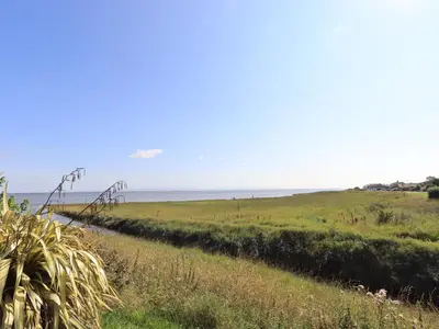 a path through a field with the ocean in the background at Solway Firth View in Annan