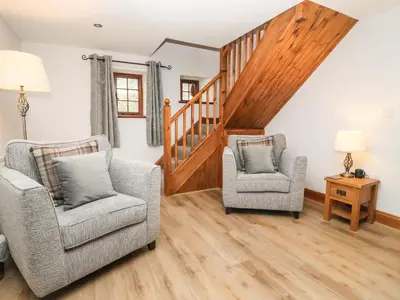 a living room with two chairs and a staircase at Fryston Cottage in Keswick