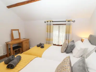 two twin beds in a room with a window at Fryston Cottage in Keswick
