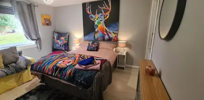 a bedroom with a bed with a painting of a deer at Modernised 1720s cottage Newton Stewart Scotland in Newton Stewart