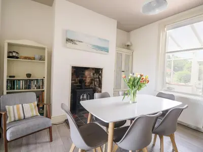 a dining room with a table and chairs and a fireplace at Pow-Wow Shore Cottage in Annan