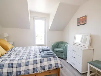 a bedroom with a bed and a tv and a chair at Pow-Wow Shore Cottage in Annan
