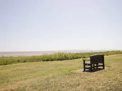 a bench sitting in a field looking out at the ocean at Pow-Wow Shore Cottage in Annan