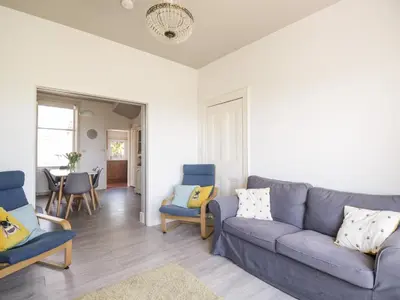 a living room with a blue couch and chairs at Pow-Wow Shore Cottage in Annan