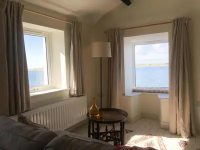 a living room with a couch and two windows at Waterside in Ravenglass