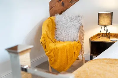 a yellow chair with a blanket sitting next to a bed at Luxury Studio Apartment - Town Centre in Whitehaven