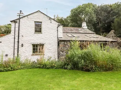 an old white house with a grass yard at Eagle Farmhouse in Glenridding