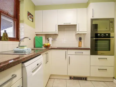 a kitchen with white cabinets and a sink at Derwent Haven in Keswick