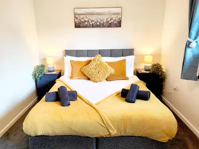 a bedroom with a large bed with yellow blanket at Terrance House, modern, spacious in Carlisle
