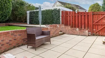 a chair sitting on a patio next to a brick fence at Leeward House - Donnini Apartments in Ayr