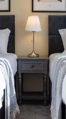 a lamp on a table between two beds at Leeward House - Donnini Apartments in Ayr