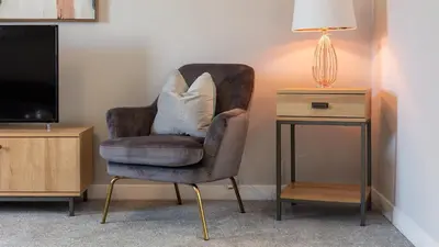a chair with a pillow on it next to a side table at Leeward House - Donnini Apartments in Ayr