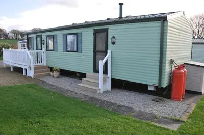 a green tiny house with a porch and a fire hydrant at Happy Days Holiday Home Whithorn2 in Newton Stewart