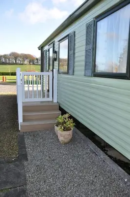 a green trailer with a porch and a potted plant at Happy Days Holiday Home Whithorn2 in Newton Stewart