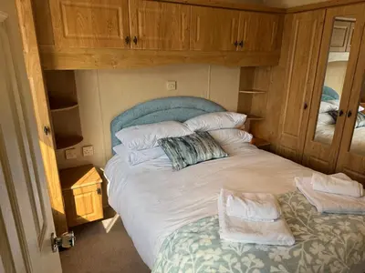 a bedroom with a large white bed with a mirror at Happy Days Holiday Home Whithorn2 in Newton Stewart