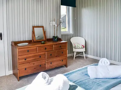 a bedroom with a dresser and a mirror on top of it at Woodend Farmhouse Halmyre in Haugh of Urr
