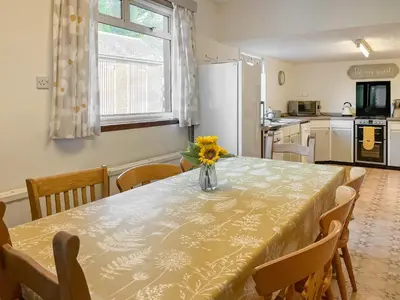 a dining room table with a vase of flowers on it at Woodend Farmhouse Halmyre in Haugh of Urr