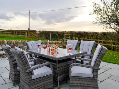 a table with chairs and wine glasses on a patio at Inverallan in Amisfield Town