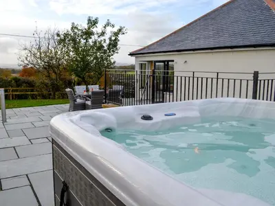 a jacuzzi tub on a patio in front of a house at Inverallan in Amisfield Town