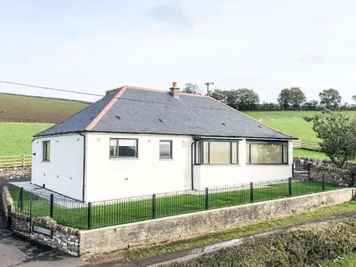 a white house with a fence in a field at Inverallan in Amisfield Town