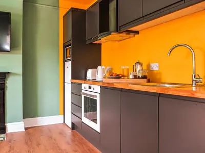 a kitchen with orange and green walls and a sink at Holst Apartment in Newton Stewart