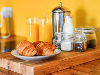 a plate of croissants on a wooden table with drinks at Holst Apartment in Newton Stewart