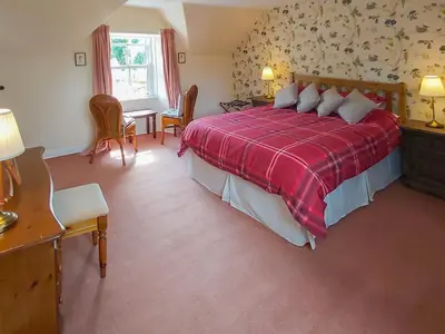 a bedroom with a large bed with a red blanket at Uk35715 - South Cottage in Teviothead