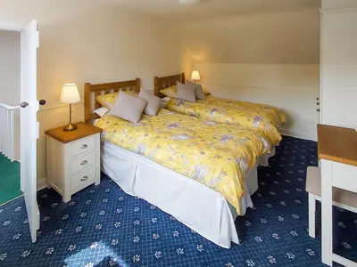 a bedroom with two beds and a table and a night stand at Uk35715 - South Cottage in Teviothead