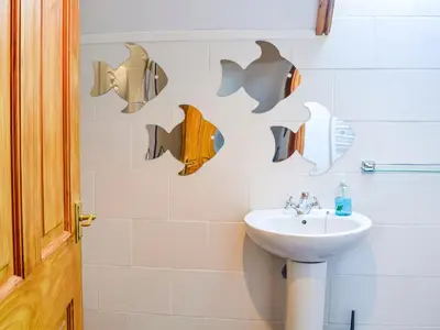 a bathroom with a sink and shark decals on the wall at Hammy's Cottage in Drummore