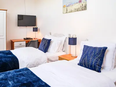 a bedroom with two beds and a tv on a wall at Hammy's Cottage in Drummore
